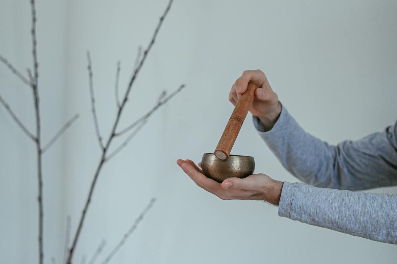 Person holding a Tibetan singing bowl indoors, promoting peace and mindfulness.